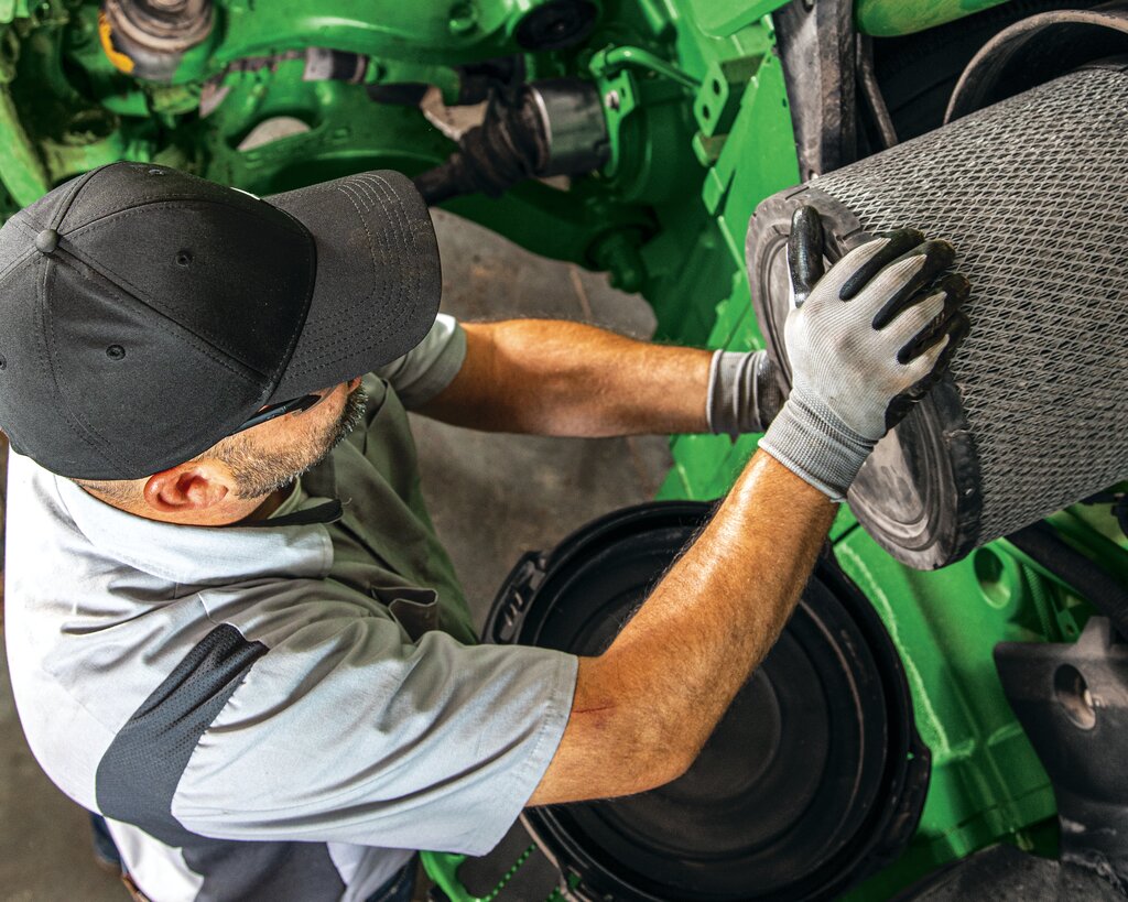 A service technician maintaining John Deere equipment