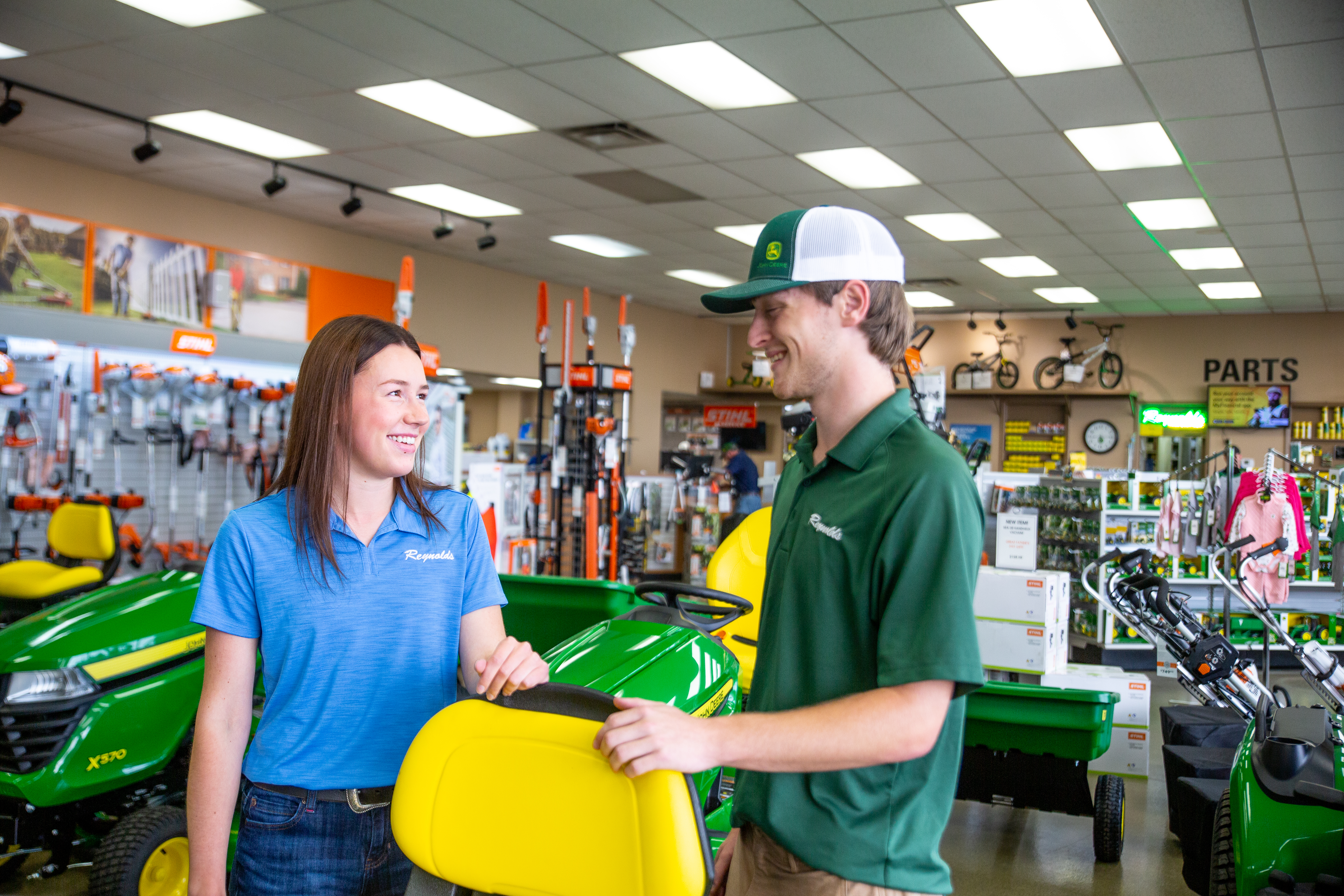 Two Reynolds Equipment team members talking in a dealership showroom