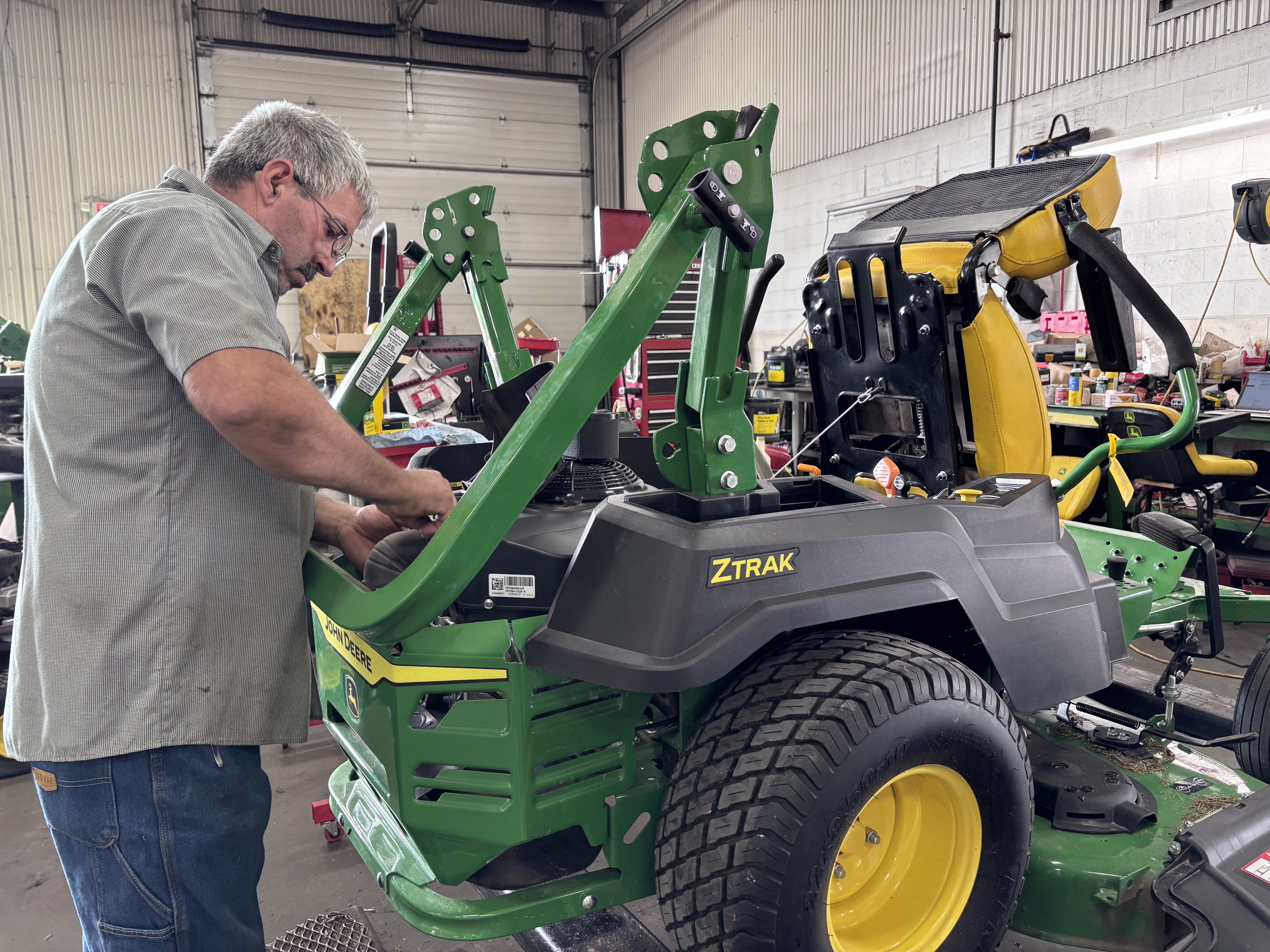 Reynolds technician performing maintenance on a John Deere zero-turn mower