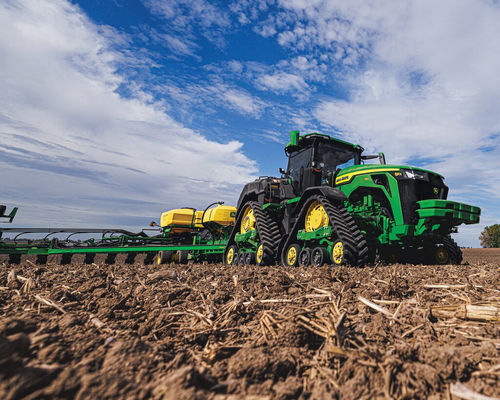 John Deere tracked tractor pulling a planter in the field