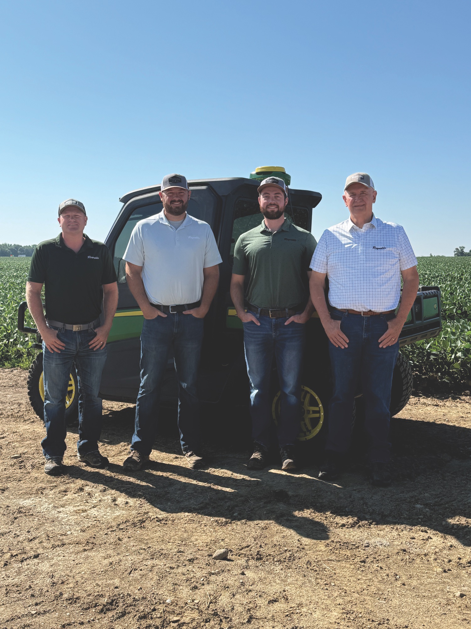 Four Reynolds Farm Equipment team members standing together in a field